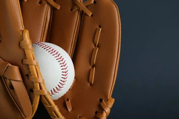 Catcher\'s mitt and baseball ball on dark background, closeup with space for text. Sports game