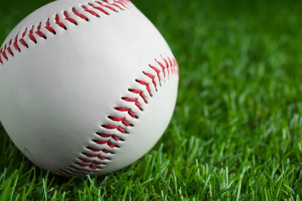 Baseball ball on green grass, closeup with space for text. Sports game
