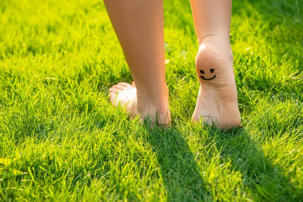 Teenage girl with smiling face drawn on heel walking outdoors, closeup