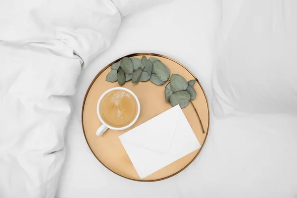 Tablett Mit Tasse Kaffee Umschlag Und Eukalyptuszweig Auf Weißem Bett — Stockfoto