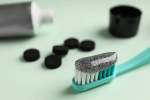 Brush with charcoal toothpaste on white background, closeup