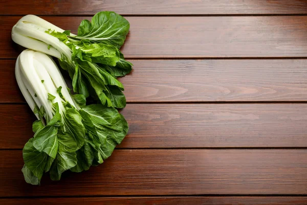 stock image Fresh green pak choy cabbages on wooden table, flat lay. Space for text