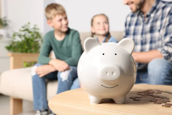 Happy family at home, focus on piggy bank. Space for text