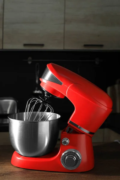 Modern red stand mixer on wooden table in kitchen