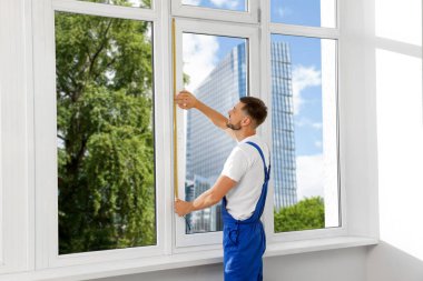 Worker measuring plastic window indoors. Installation process