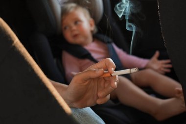 Anne arabada sigara ve çocukla, yakın plan. Çocukların yanında sigara içme.
