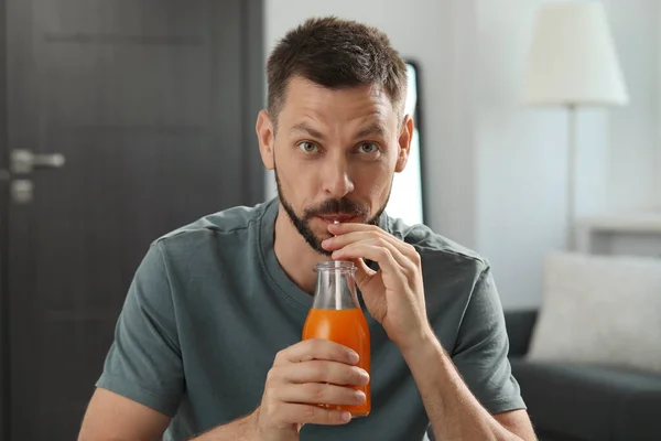 男人在家里用瓶子喝美味的果汁 — 图库照片