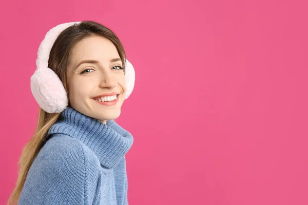 ピンクの背景に暖かい耳飾りを身に着けている幸せな女性 テキストのためのスペース — ストック写真