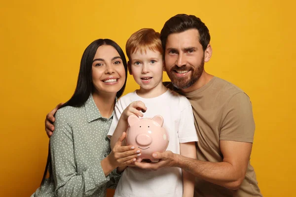 Família Feliz Com Banco Porquinho Cerâmico Fundo Laranja — Fotografia de Stock