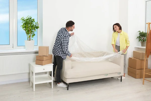 Joyeux Couple Prenant Film Plastique Canapé Dans Nouvel Appartement Jour — Photo