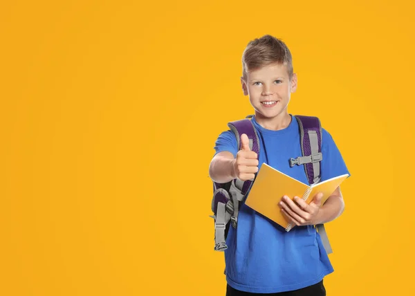 Симпатичний Хлопчик Шкільними Канцелярськими Приладдям Показує Великі Пальці Жовтому Тлі — стокове фото
