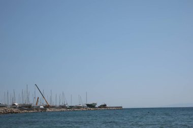 Güneşli bir günde tekneli ve sakin denizli iskele manzarası.