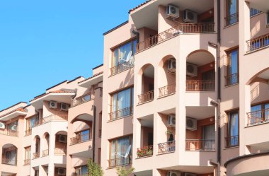 Exterior of beautiful residential building with balconies against blue sky