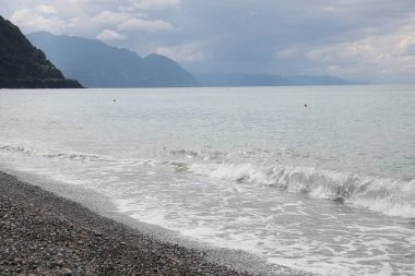 Güzel deniz kıyısı manzarası ve bulutlu tepeler.