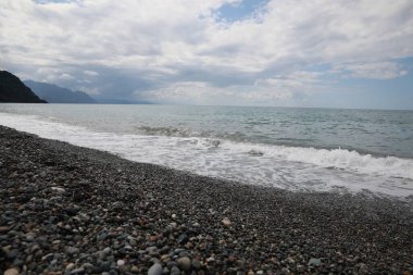 Güzel deniz kıyılarının ve gökyüzünün altındaki kabarık bulutların resimli görüntüsü.