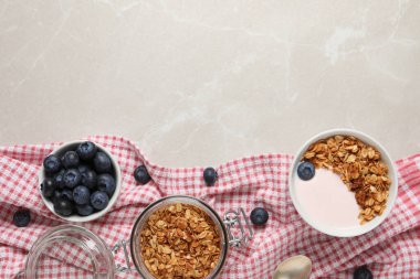 Bowl of yogurt with granola and blueberries on grey marble table, flat lay. Space for text