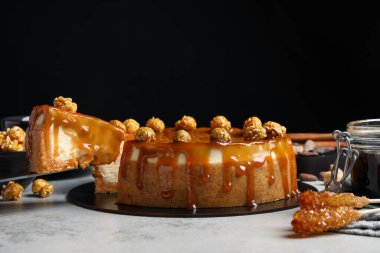 Taking piece of delicious caramel cheesecake with popcorn on light grey table