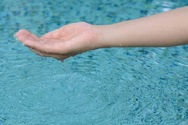 stock image Girl holding water in hand above pool, closeup