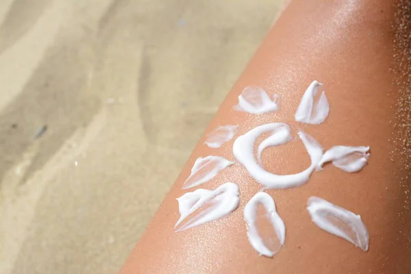 Sun drawn with sunscreen on woman\'s leg at beach, closeup. Space for text