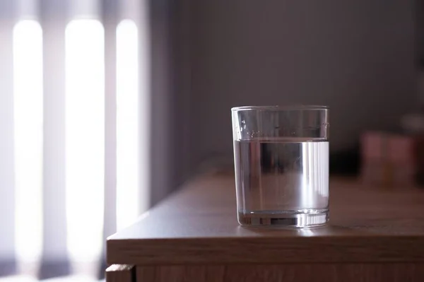 Glass of water on wooden table in room. Space for text