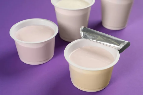 Пластиковые Чашки Вкусным Йогуртом Фиолетовом Фоне — стоковое фото
