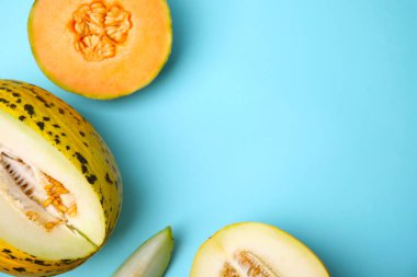 Tasty colorful ripe melons on light blue background, flat lay. Space for text