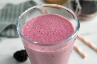 Beyaz masada bir bardak böğürtlenli smoothie, yakın plan.