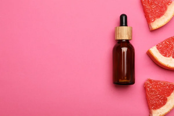 Butelka Olejku Cytrusowego Świeże Plasterki Grejpfruta Różowym Tle Płaskie Układanie — Zdjęcie stockowe