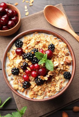 Tahta masada, böğürtlen ve sütle servis edilen bir kase müsli.