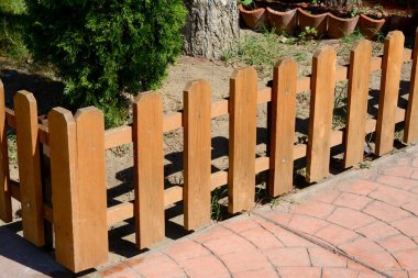 Açık havada güneşli bir günde, thuja yakınlarında küçük ahşap çitler.