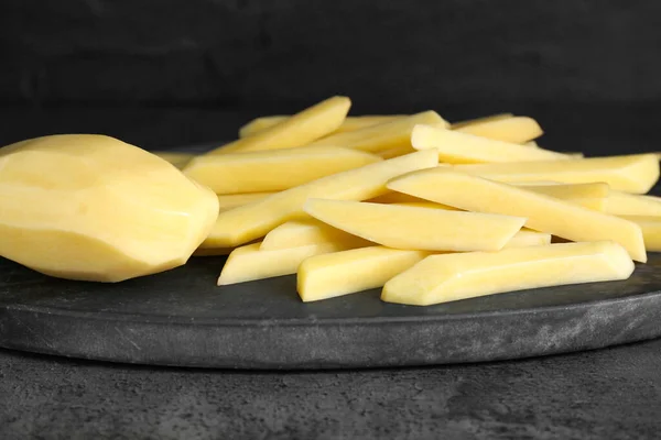 stock image Whole and cut raw potatoes on grey table, closeup. Cooking delicious French fries