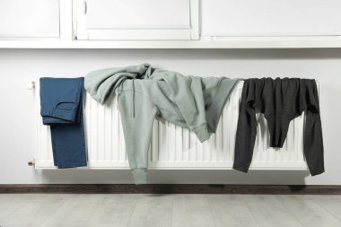 Pantolon, kapüşon ve balıkçı yaka kazak pencerenin yanındaki ısıtma kaloriferinde.