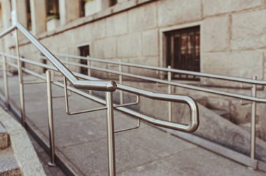 Tiled ramp with shiny metal railings outdoors