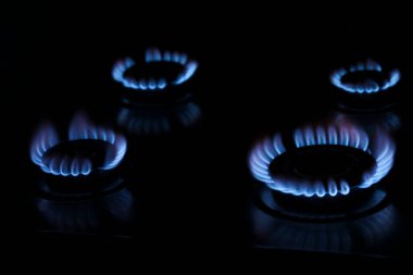 Gas cooktop with burning blue flames in darkness