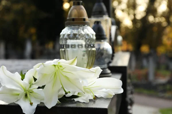 stock image White lilies and grave lights on granite tombstone outdoors, space for text. Funeral ceremony