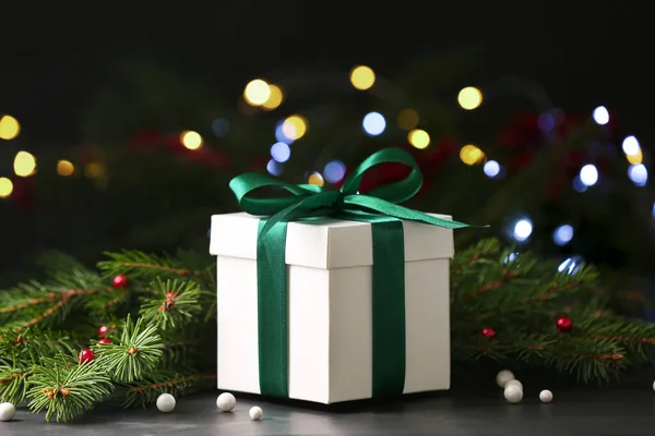 圣诞礼物黑色桌子上美丽的礼品盒和枞树枝条 挡住朦胧的节日灯火 — 图库照片