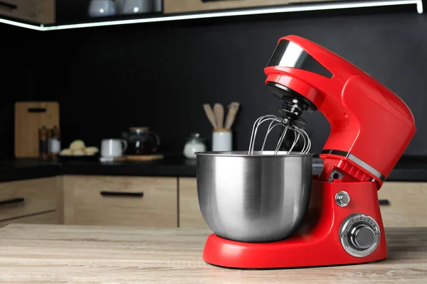 Modern stand mixer on wooden table in kitchen, space for text. Home appliance