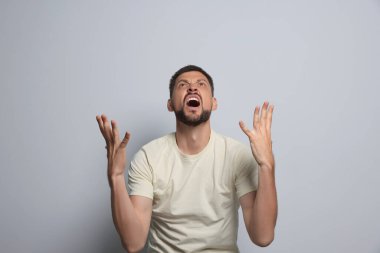 Aggressive man shouting on grey background. Hate concept