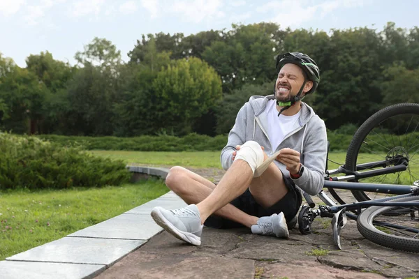 Homem Aplicando Bandagem Seu Joelho Perto Bicicleta Livre Espaço Para — Fotografia de Stock