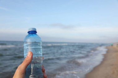 Deniz kenarında plastik şişe tutan kadın, yakın plan. Metin için boşluk