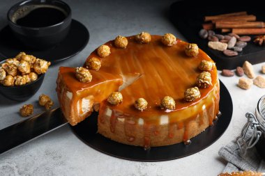 Taking piece of delicious caramel cheesecake with popcorn on light grey table