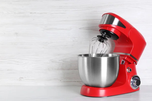 Modern red stand mixer on white marble table, space for text