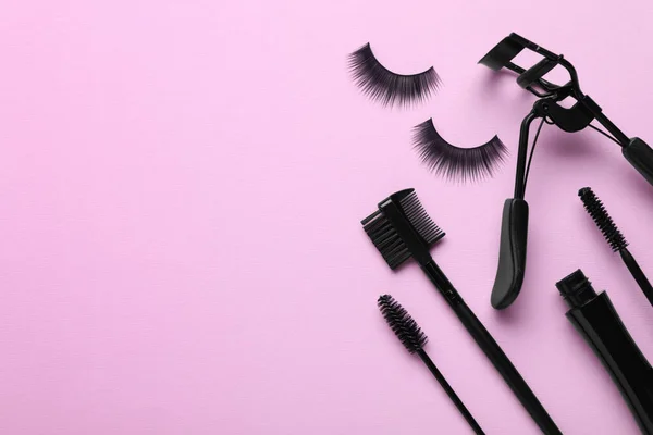 Flat lay composition with fake eyelashes on pink background, space for text