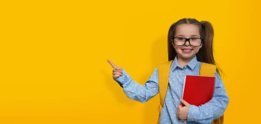 Okula ilk gelişim. Sarı arka planda gözlük takan sevimli küçük bir çocuk, mesaj için yer var. Pankart tasarımı