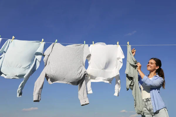 Kobieta Wiszące Ubrania Szpilki Myjni Suszenia Przed Błękitnym Niebem — Zdjęcie stockowe