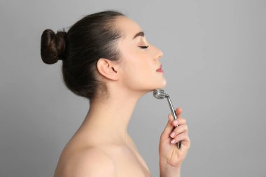 Gri arkaplanda metal yüz silindiri kullanan kadın