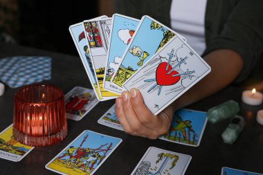 İçerideki gri masada tarot kartlarıyla falcı, yakın plan.