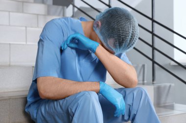 Exhausted doctor sitting on stairs in hospital