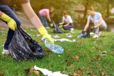 Plastik torbalı adam parkta çöp topluyor, yakın plan.