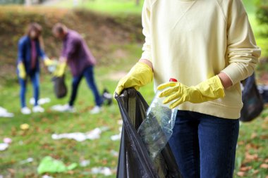 Plastik çantalı kadın parkta çöp topluyor, yakın plan.
